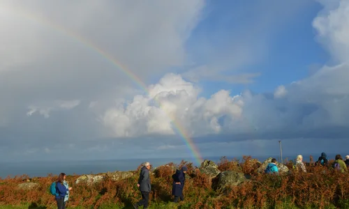 Walkers in the Penwith landscape near Zennor with a rainbow behind
