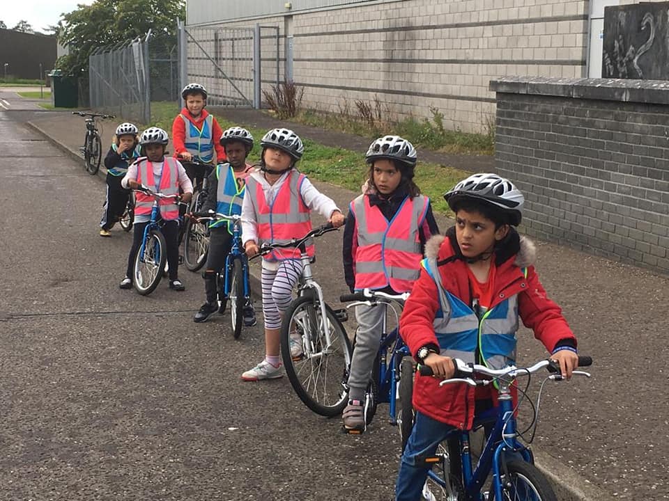 a group of children with bikes standings along a pavement