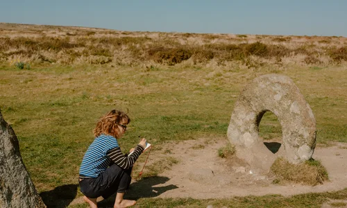 Child making notes next to the Men-an-Tol holed stone