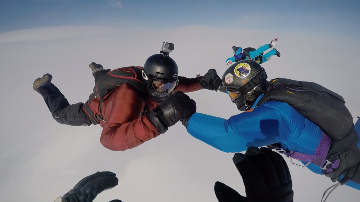 Four skydivers attempt to lock hands during a jump